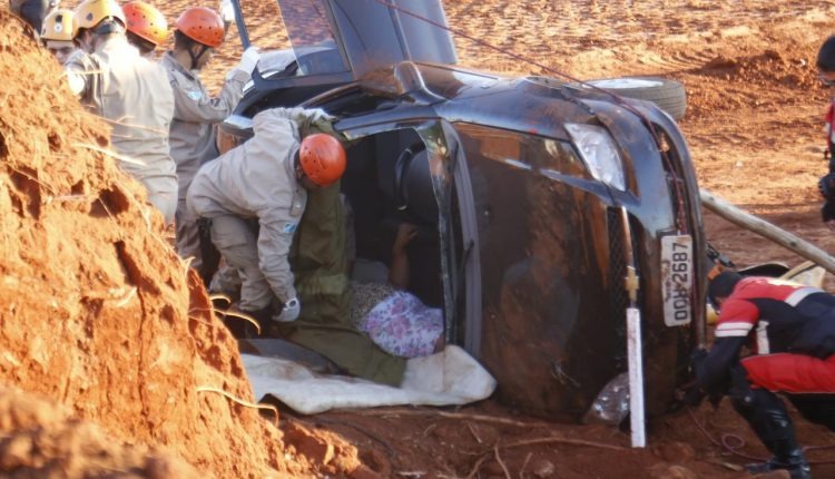 Motorista se distrai ao pegar objeto no carro, capota e invade canteiro de obra