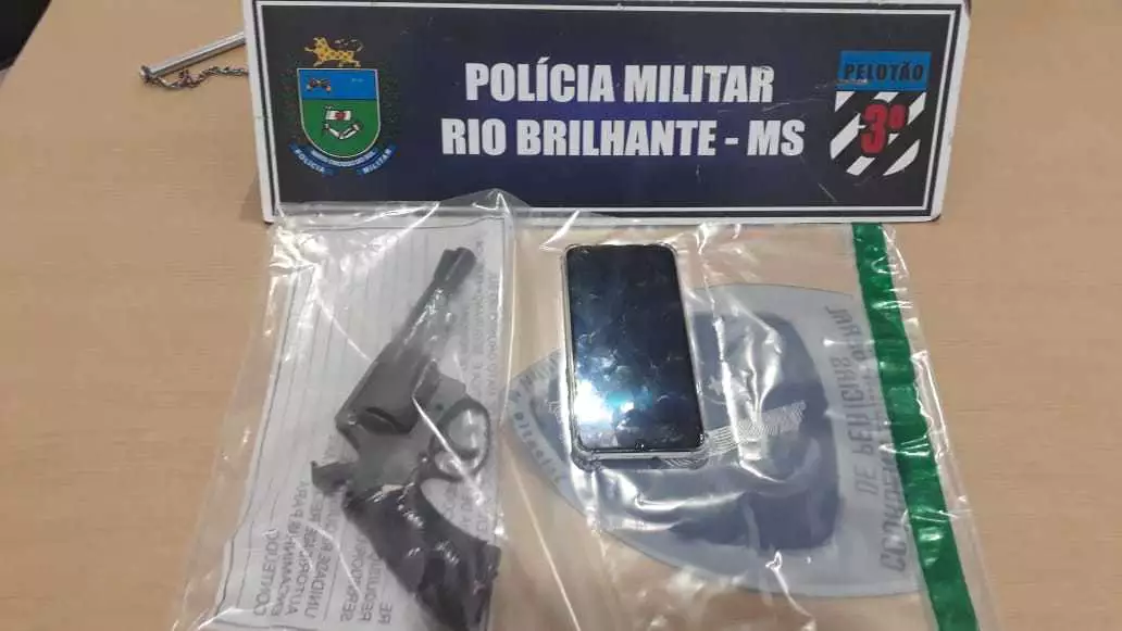 Revólver (esq) encontrado atrás do bebedouro e celular (dir) roubado pelos homens (Foto/Divulgação) 