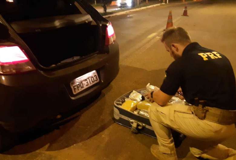 Policial retirando os tabletes de supermaconha da mala. - Crédito: (Divulgação PRF) 