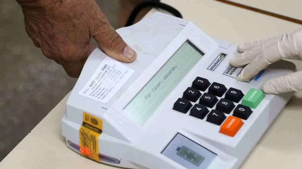 Mesário orienta eleitor para uso do leitor biométrico. (Foto: Roberto Jayme/Arquivo/TSE)